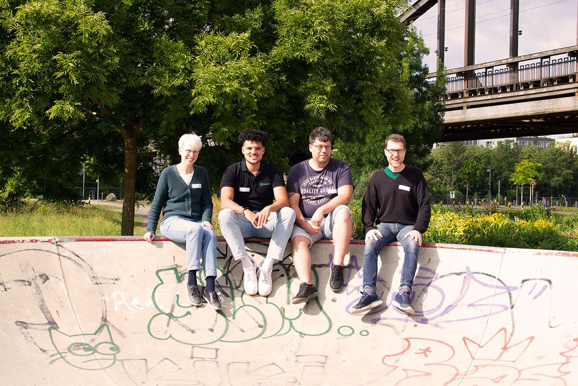 Gruppenfoto der Green IT Community mit einer Frau und drei Männern, die auf der Kante einer Halfpipe sitzen.