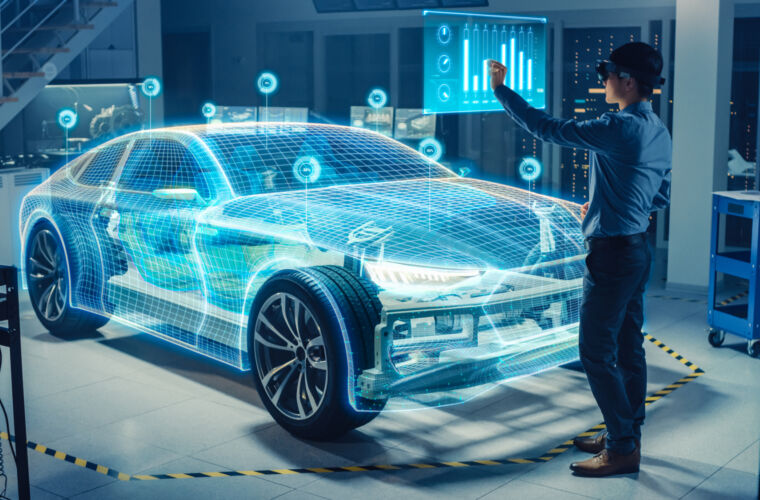 In einem modernen Laborumfeld steht eine Person vor einem Auto, das von einem holografischen Gittermodell umgeben ist. Die Person interagiert mit einem schwebenden, digitalen Display, das Diagramme und Daten anzeigt.